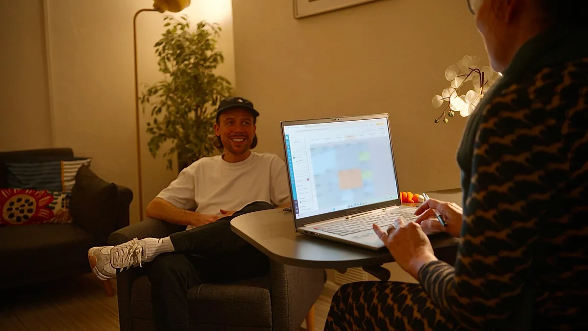 A relaxed NeuroFX assessment in Bedford: a patient sitting comfortably in an armchair while the clinician works at a laptop in a warm, softly lit consulting room.