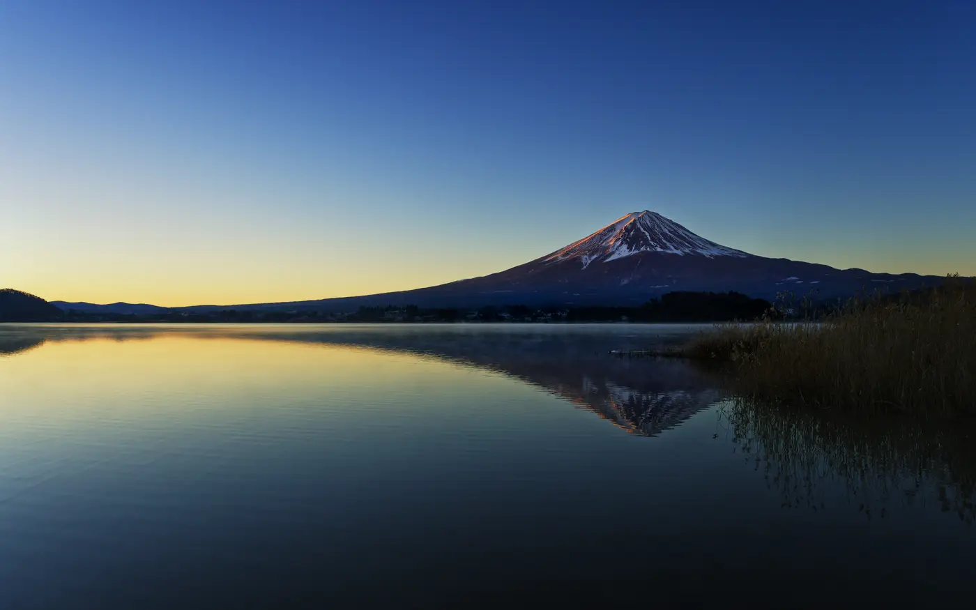 A calm mountain reflected in still lake water at first light