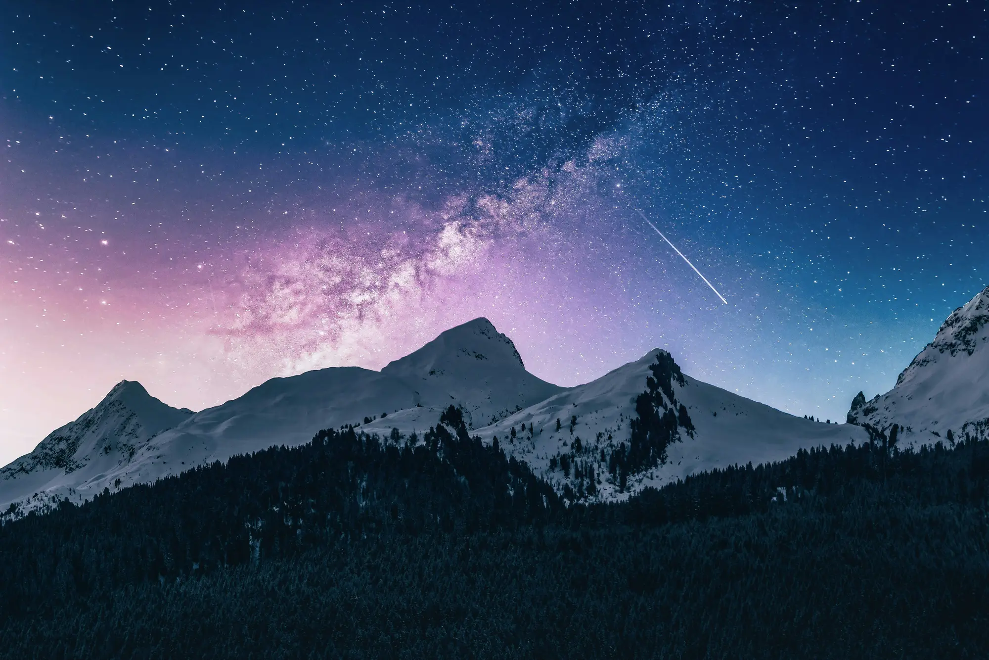 Snow-dusted mountains beneath a night sky filled with stars and the Milky Way