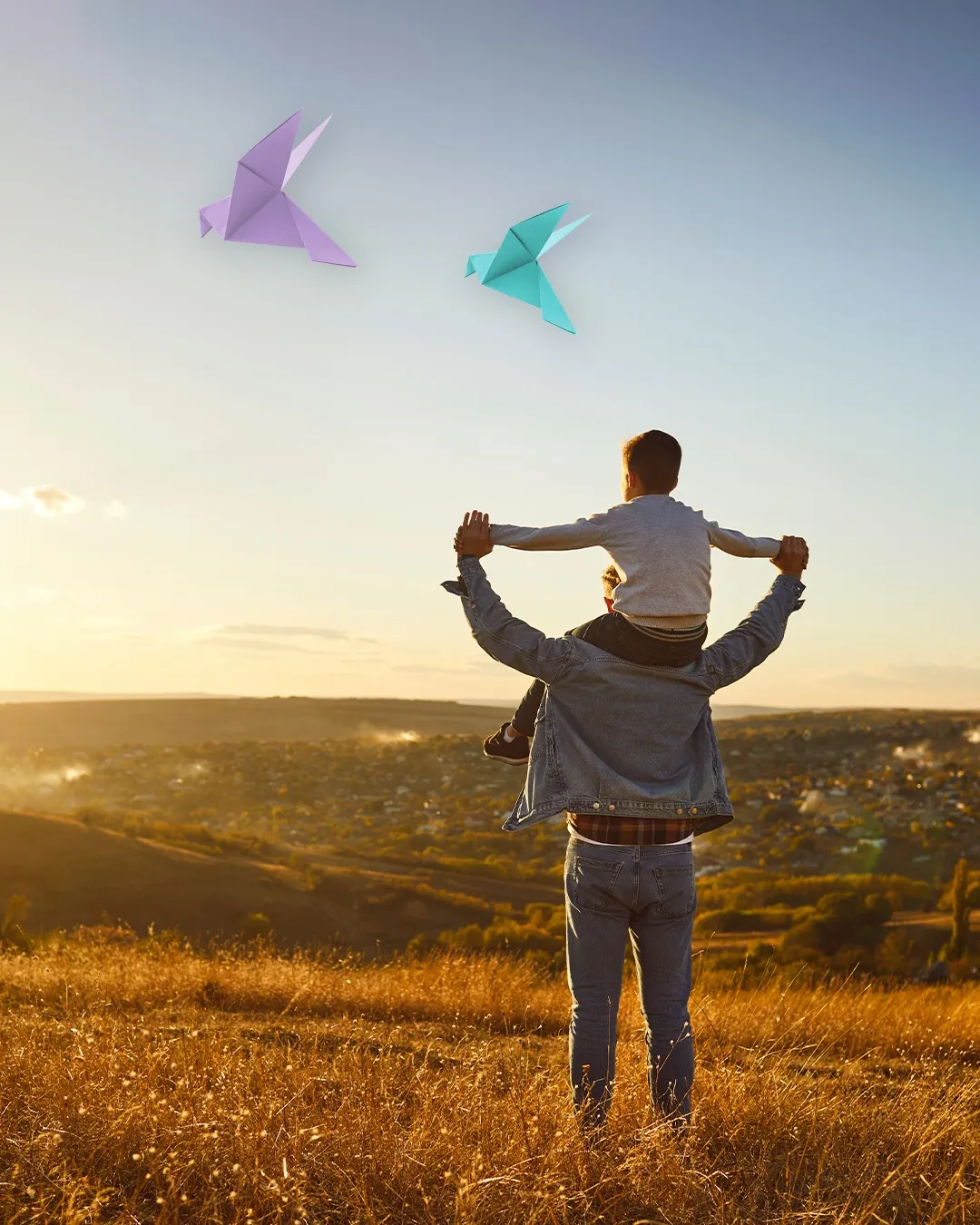 A parent carrying a child on their shoulders at sunset, with origami birds rising into the sky